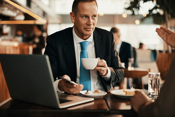 Mature businessman talking to a partner at the cafe
