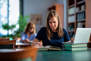 A visually impaired woman sitting and studying in the university library