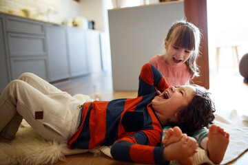 Playful siblings share a joyful moment in the living room - obrazy, fototapety, plakaty