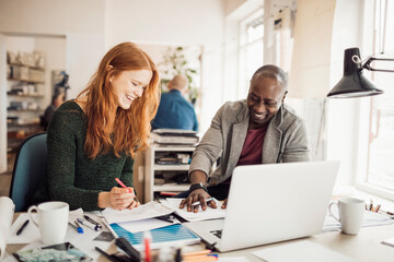 Two focused professionals discussing a project on a laptop in a modern workspace