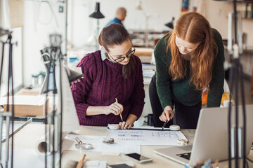 Two female designers intently reviewing architectural blueprints in the office
