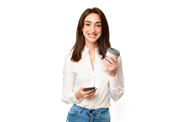 Fototapeta premium Young caucasian woman over isolated chroma key background holding coffee to take away and a mobile