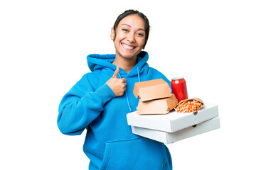 Young Uruguayan woman holding pizzas and burgers over isolated chroma key background giving a thumbs up gesture