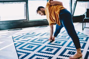 Hipster guy doing stretching exercises in stylish flat to lead healthy lifestyle