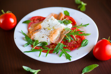 Cooked poached egg with herbs, lightly salted salmon and tomatoes with spices .