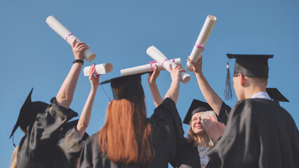 College graduates join hands with their diplomas. The concept of friendship.