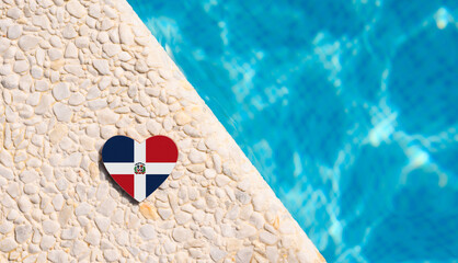 Dominican Republic flag in the shape of a heart near the pool in the hotel. Holiday concept in...