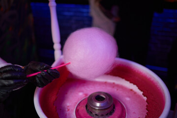 Hand rolling cotton candy in candy floss machine. Making candyfloss