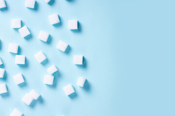 Sugar cubes on blue background, flat lay scene with copy space