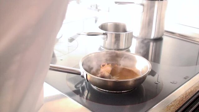 Un cuoco prepara una coscia di pollo in padella aggiungendo del brodo