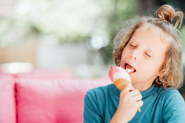 Portrait of boy with closed eyes eating cone ice cream. Child licking ice cream and enjoying summer...