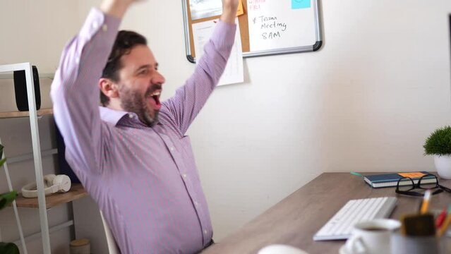 Excited man celebrating a big sale or winning a prize while looking at his computer at the office