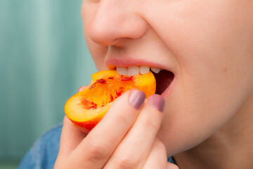 Close-up of a Caucasian woman eating a slice of fresh peach.