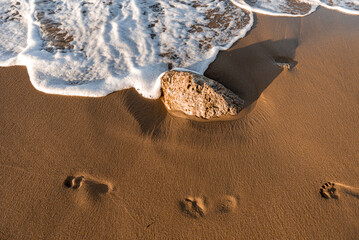 Directly above view of waves breaking on shore at sunset.