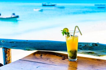 Glass of orange mojito cocktail. Ocean at the background