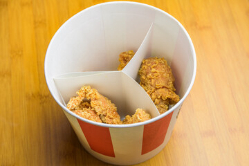 Bucket with crispy fried chicken on a table