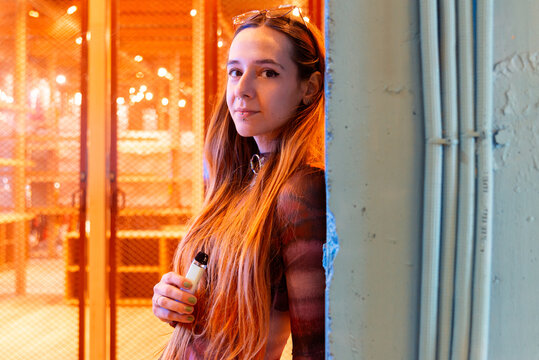 Young woman holding an e-cigarette against serene urban backdrop