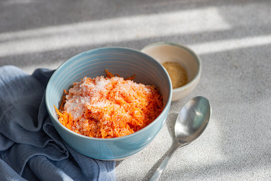 Carrot dessert with chopped raw carrot vegetable with sugar served on bowl on table