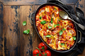Stuffed pasta cannelloni with minced meat baked in  tomato sauce in a skillet. Top view with copy space.