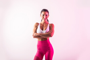 Sportive beautiful woman training with athletic body and sportswear doing workout, colorful lighting and background