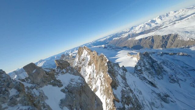 FPV drone flying above the ridges of a snow-covered French mountain on a sunny day
