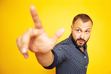 Touch it concept. Close up portrait of charismatic 35 years old man standing over yellow background showing something with his index finger. Studio shot