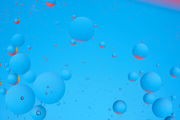 Macro photo with circles oil droplets water surface. Abstract blue and red background with oil bubbles.