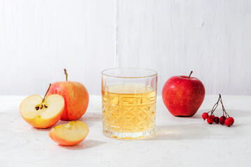 Fresh ripe apples and glass of apple juice or cider on white table. Autumn harvest, Thanksgiving concept
