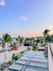 Rooftop view of the resort beach featuring palm trees, cabanas and the Gulf of Mexico at golden hour