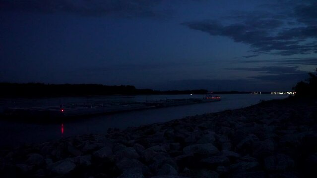 towboat with barges entering the Chain of Rock Bypass Canal from the Mississippi River below Alton, IL, night scenery at dawn