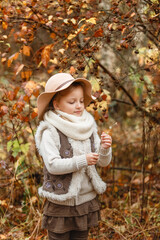 Portrait of a smiling young girl in a hat in an autumn park.