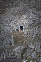 Impressive entrance in to the massive cave called Vladikine Ploce under a conical mountain peak on Old mountain in Serbia - 670228538