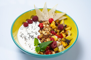 fruit, vegetarian salad with pear, raspberry, flakes on a colored plate on a white background. Light breakfast, morning	
