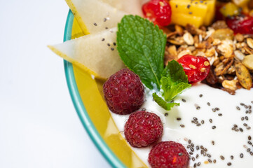 fruit, vegetarian salad with pear, raspberry, flakes on a colored plate on a white background. Light breakfast, morning	
