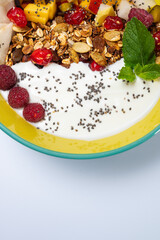 fruit, vegetarian salad with pear, raspberry, flakes on a colored plate on a white background. Light breakfast, morning	
