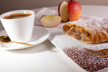 Paired pieces of delicious strudel stuffed with apples and cinnamon on a light plate on a light background. Place for writing. Close up view. Homemade Ukrainian pastries	

