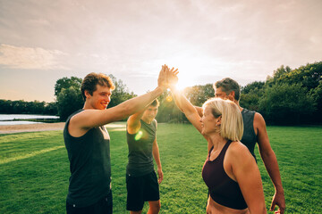 a positive family of runners at the park on sunrise clasping hand in group