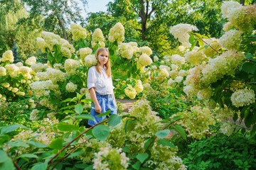 Cute teenage girl in flowering hydrangea bushes.