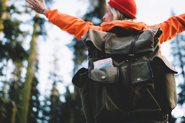 Back view of positive female hiker with backpack travelling and enjoying adventure in mountains
