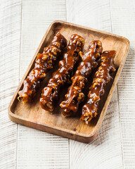 Fresh churchkhela on a wooden plate on a wooden background. Oriental sweets.