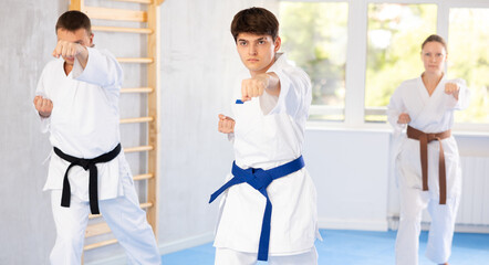 In gym, certified master coach conducts karate kata lesson with students and shows sequence of actions when conducting close fight