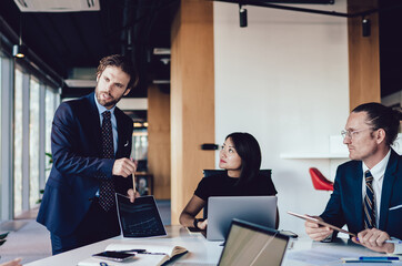 Businessman carrying presentation communicating with employees sitting at table