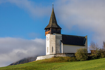 Fototapeta premium Reformierte Kirche church in the autumn Alps. Amazing landscape with small chapel on sunny meadow at Davos Frauenkirch, Davos, Switzerland