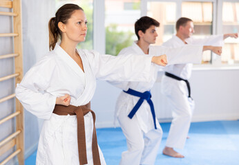 Fototapeta na wymiar In gym, certified master coach conducts karate kata lesson with students and shows sequence of actions when conducting close fight