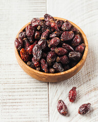 Dried rosehip on a wooden plate on a wooden background. 