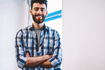 Half length portrait of successful bearded young man in casual wear smiling at camera
