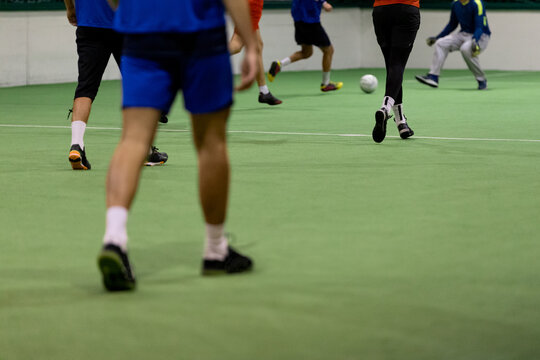Indoor soccer players with ball on artificial grass.