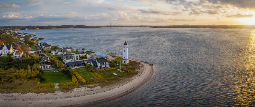 Strib Lighthouse, a picturesque historic beacon on the Danish coast, set against the backdrop of the grand Den Nye Lilleb&aelig;ltsbro (The New Little Belt Bridge). Lighthouse on the Beach in Middelfart.