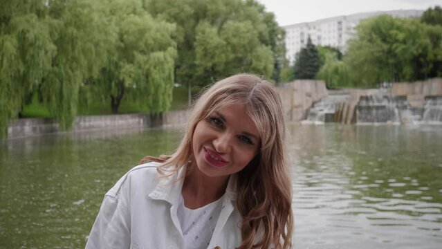 Portrait of a cheerful beautiful blonde Russian woman in a summer park