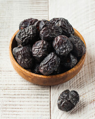 Fresh dates on a wooden plate on a white background. Oriental sweets, dried fruits